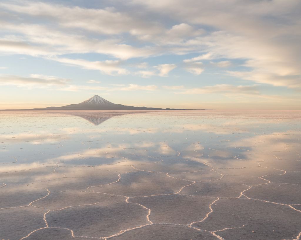 An immense salt flat under a thin sheet of water perfectly mirroring cloud